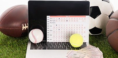 laptop near sports balls and betting list on green grass